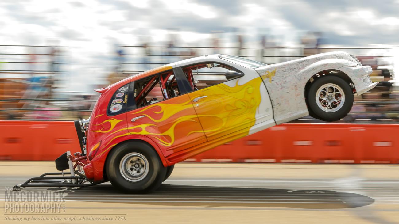 Tricked out PT Cruiser dragster doing a high-speed wheelie.