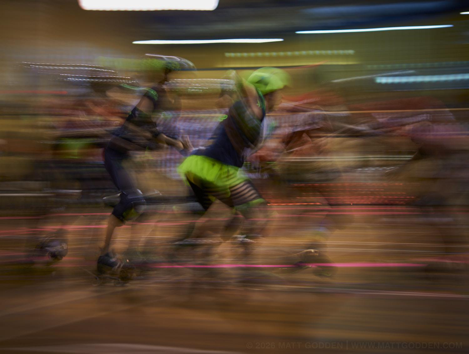 A long exposure image of roller derby competitors from the D'Viants (lime green), and the Screaming Assault Sirens (red). 2013/11/09