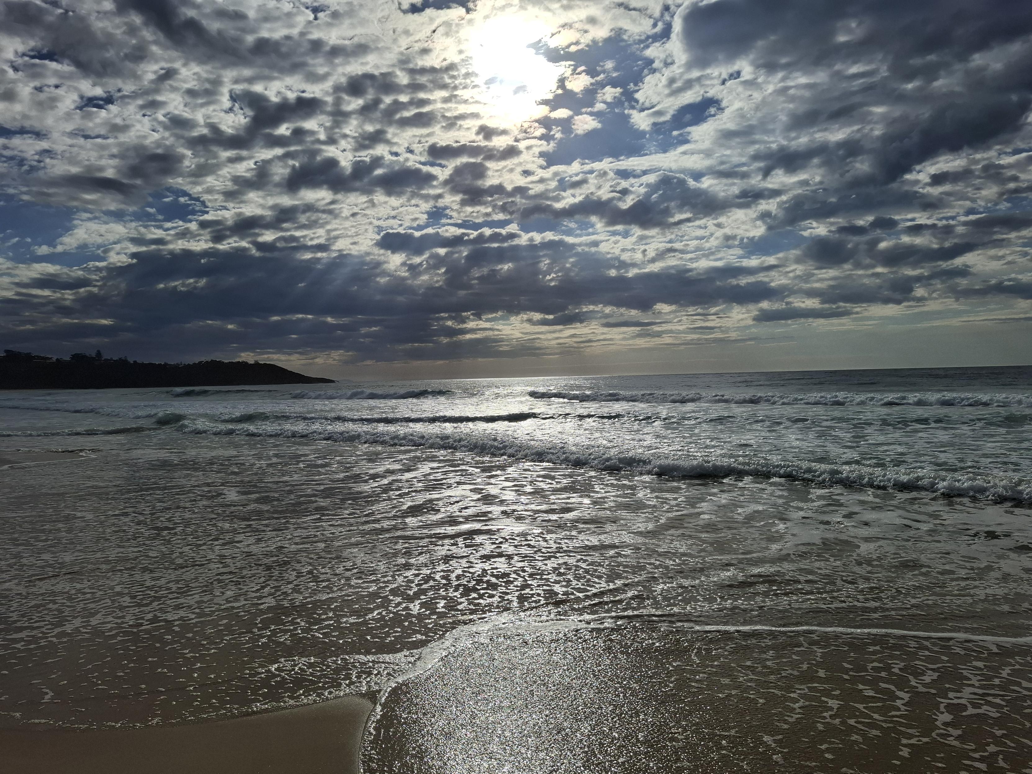 A sky filled with scattered dark clouds causinv the water and wash to shimmer.