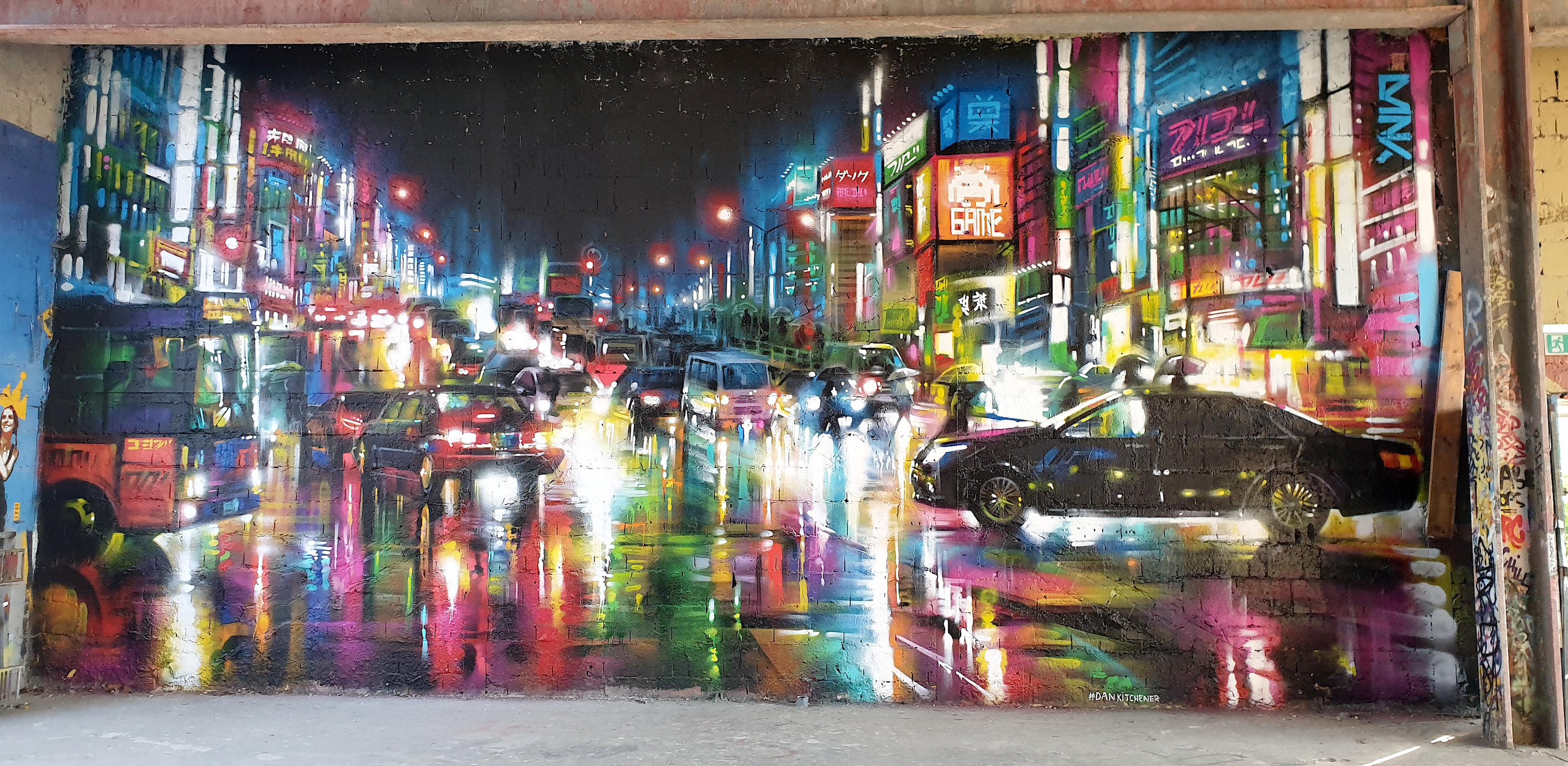 Graffiti. Sehr bunt. Zeigt eine sehr belebte Stadtstraße bei Nacht mit vielen Lichtern.