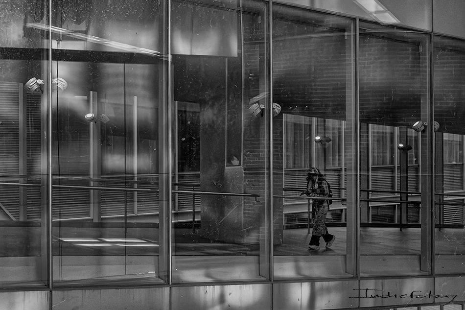 A person is passing through a glass passage as if a prison with no bars.