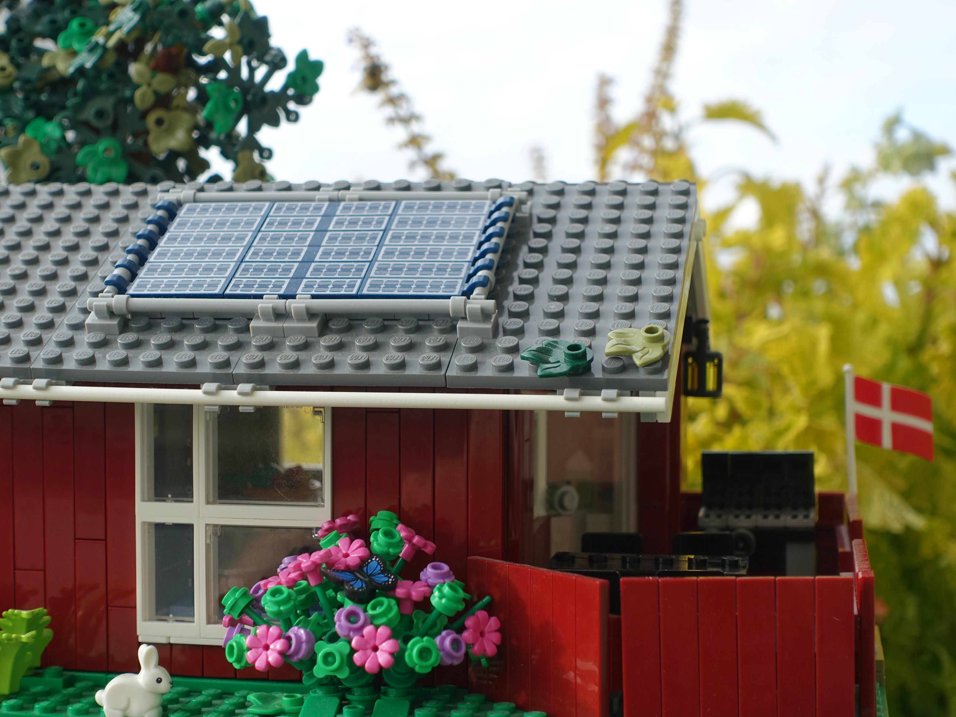 Lego model of a Danish summer cottage, pictured in front of some plants.