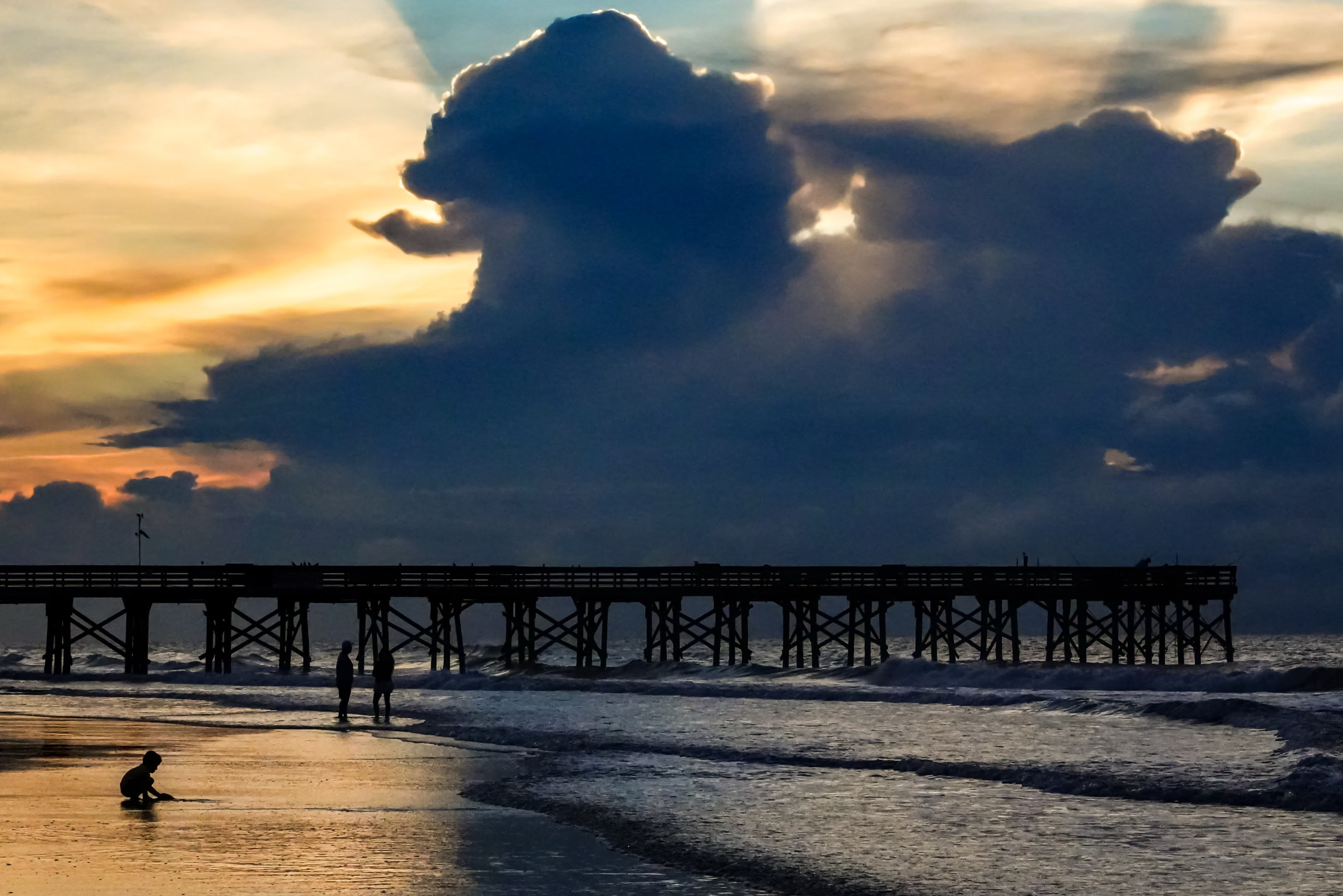 A young child plays in the sand as a storm passes off shore in Isle of Palms.