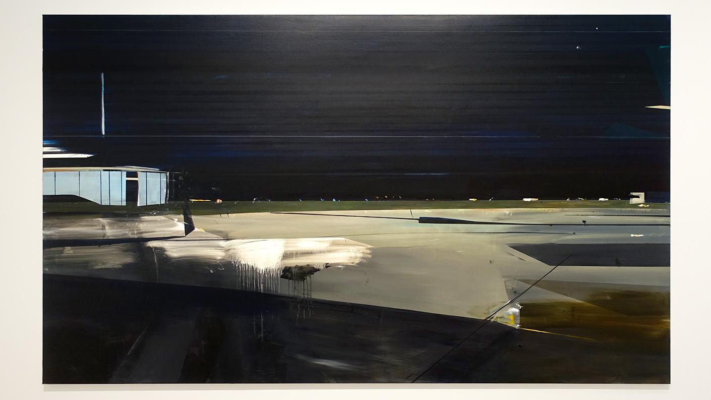 Schilderij van een abstract landschap. het lijkt wel een vliegveld in de nacht door de lichtbruine vlakken, de harde schaduwen en de enorme ruimte door de verre horizon. Links staat een bouwwerk van lichtblauwe panelen net daarin een zwarte deur. Voor onze blik is een witte vage vlek te zien waarbij er een druipend effect is toegevoegd. Hierdoor lijkt dit landschap wel op te lossen. Onder het schilderij is een donker schuin vlak alsof de bezoeker over een rand kijkt. Het geheel oogt desolaat en verlaten maar wel fascinerend. Deze kunstenaar schildert de leegte, een wereld zonder mensen, unheimisch en afstandelijk als een verlaten filmset. Daarbij maakt ze gebruik van alle onvolkomenheden en afwijkingen van de fotografische lens. Het werk trekt je naar binnen en laat je daar achter, je staat er alleen voor.