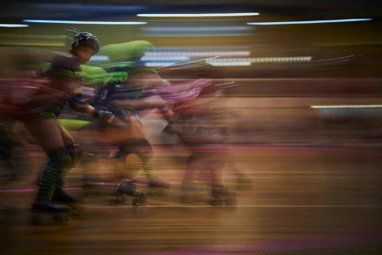A long exposure image of roller derby competitors from the D'Viants (lime green), and the Screaming Assault Sirens (red). 2013/11/09