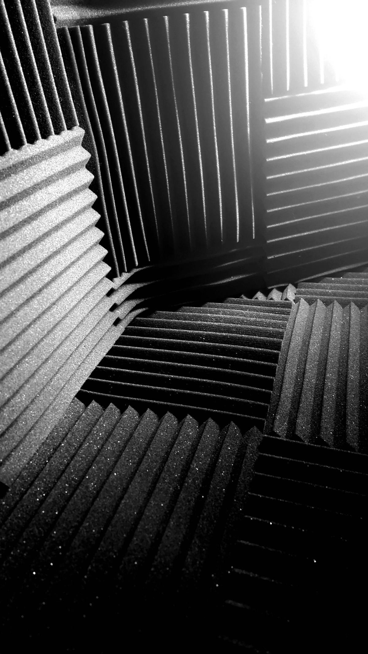 Black and white photo of a closet used as a recording space covered in acoustic foam panels.
