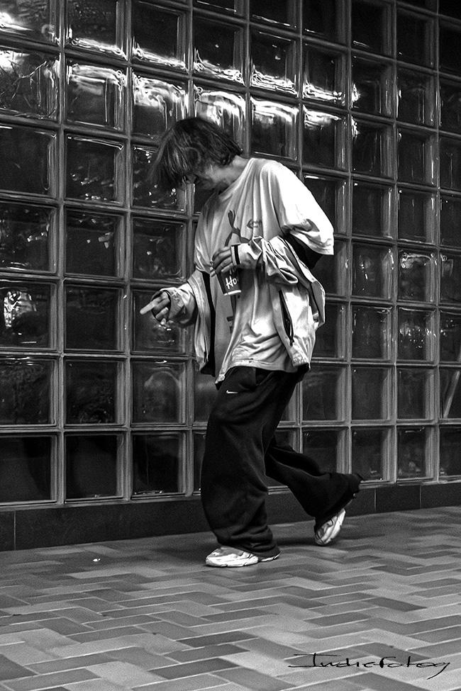 A disheveled man walking pointing his finger forward.