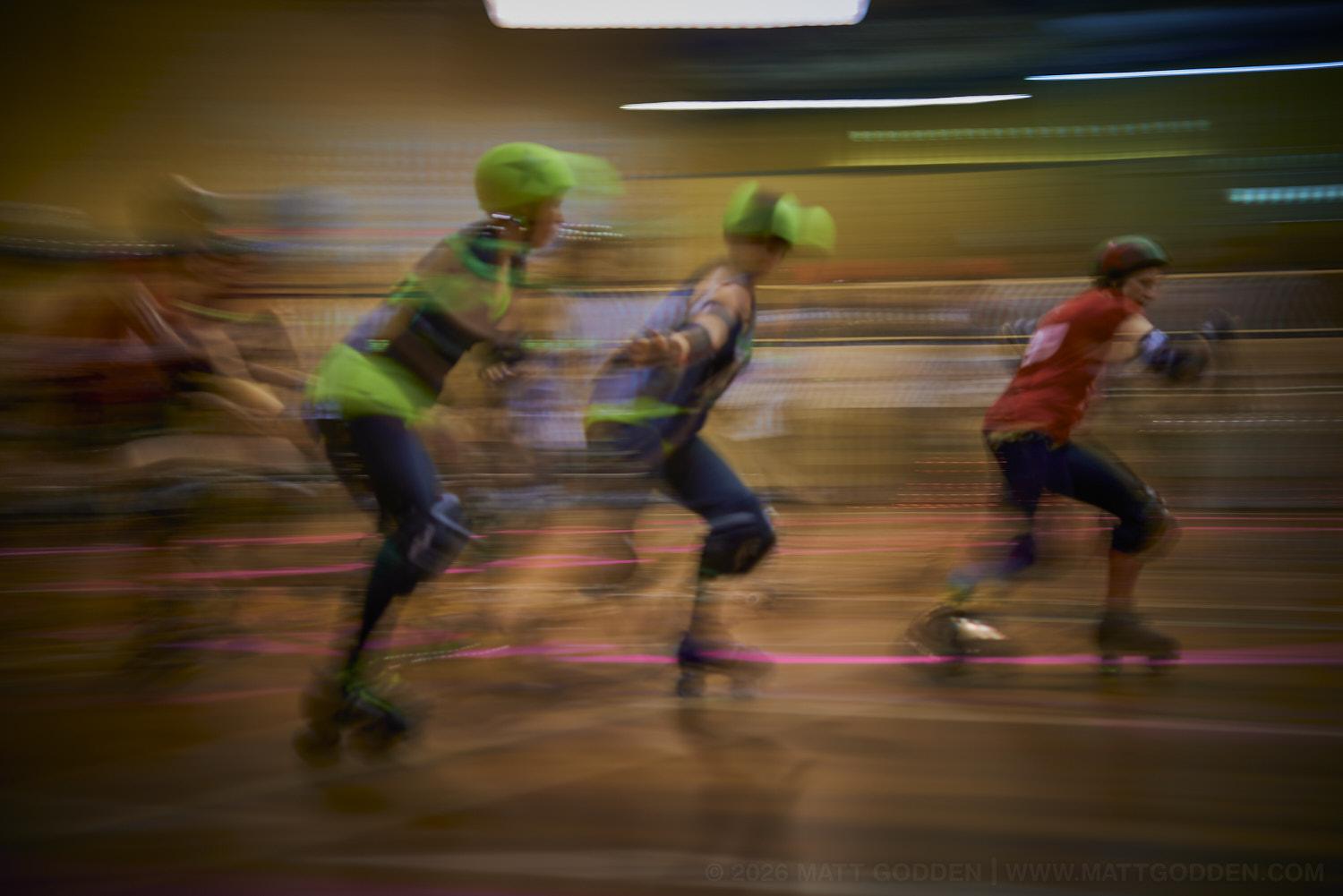 A long exposure image of roller derby competitors from the D'Viants (lime green), and the Screaming Assault Sirens (red). 2013/11/09