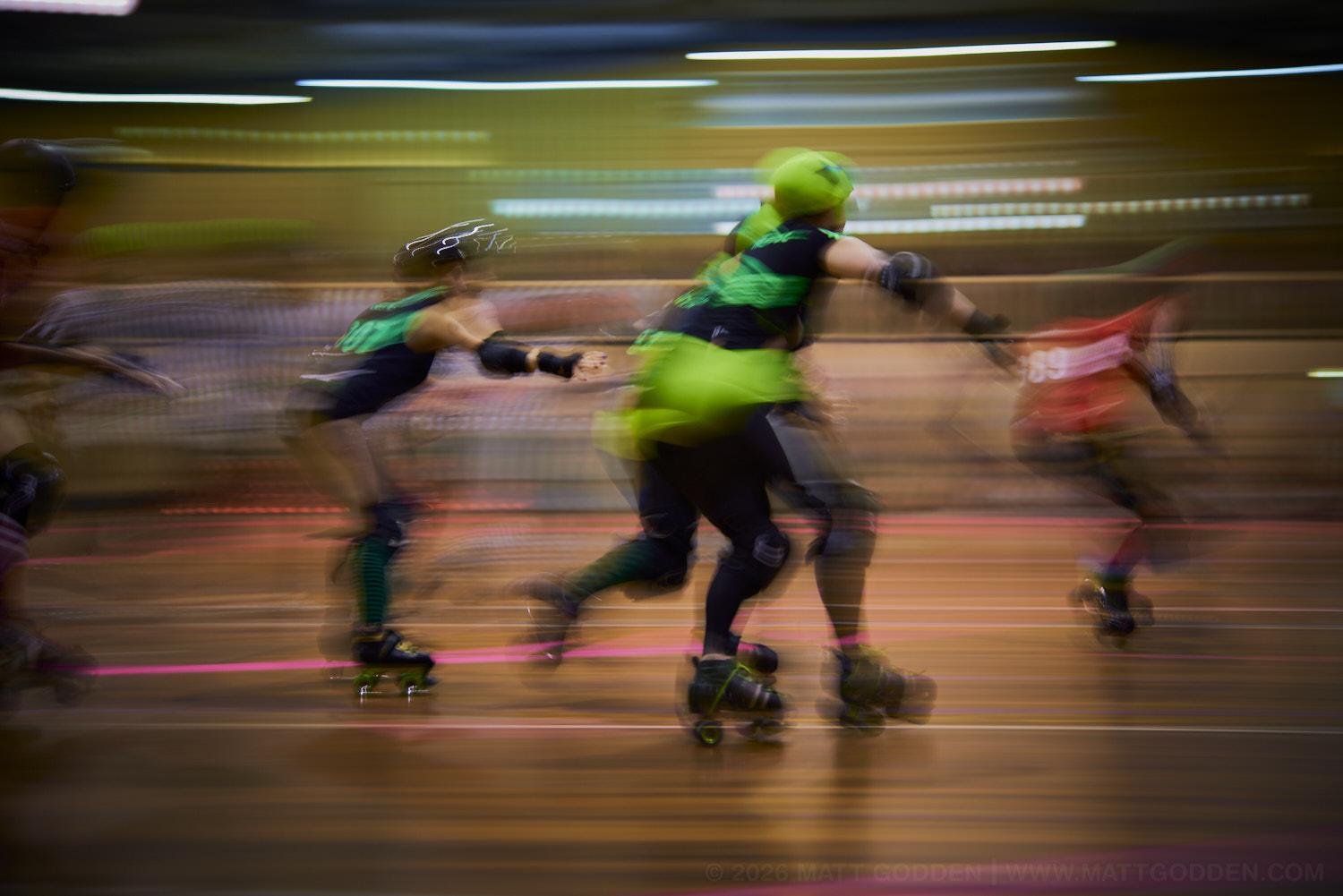 A long exposure image of roller derby competitors from the D'Viants (lime green), and the Screaming Assault Sirens (red). 2013/11/09