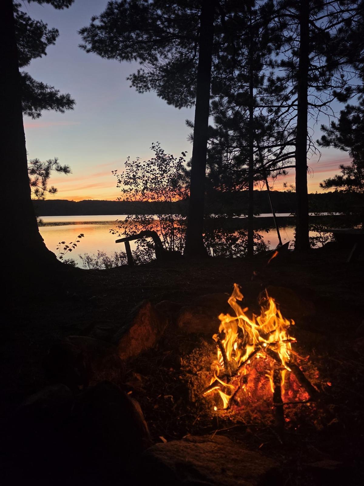 Ein schönes Lagerfeuer brennt vor einem einzigartigen Sonnenuntergang am Lake of Bays in Kanada. Kanada 2026