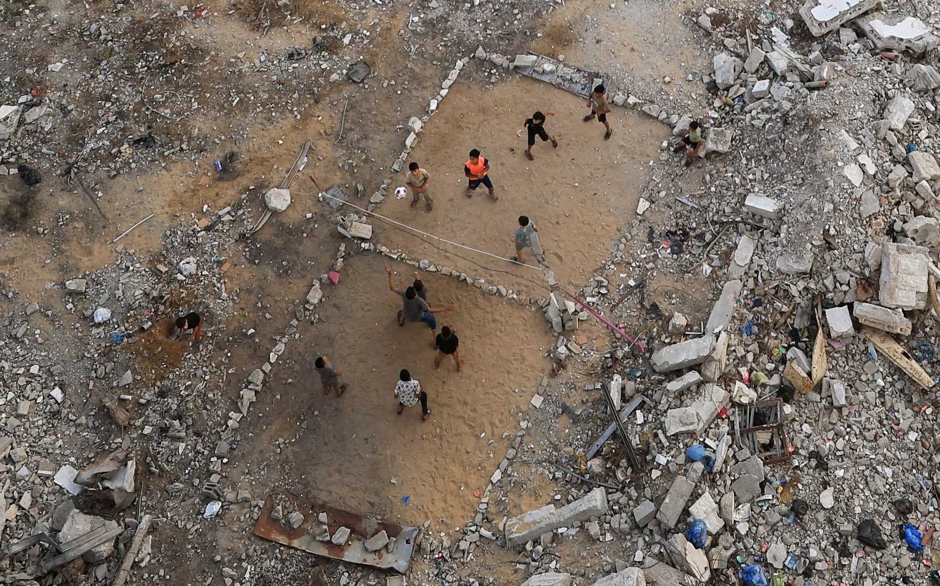 Palestinian children play volleyball amid the rubble.