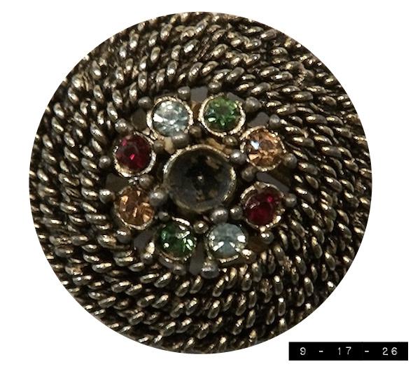Vintage Judy-Lee clip-on earring.  It's missing its center jewel but still has 8 jewels around the center: red, clear, green, yellow, red, clear, green, yellow (going clockwise from about the center left).  Those 8 jewels are surrounded by approximately 4 loops of faux gold roping.  The entire thing is about 1 inch in diameter (a good size for an earlobe cover).  Its mate is the same size and configuration - and also missing its center jewel.  I'd never heard of Judy-Lee Jewelry before finding and buying these earrings online for a whopping $2.50.  A bit of research tells me that the company was started in Chicago in 1949 by Blanche and Aldo Viano.  Apparently they sold through home sales parties rather than stores (at least at first).  They did ok in the 1950s and 1960s but shut down in 1972 - so this earring must have been made over 50 years ago.  A fine example of elderly aunt jewelry, I'd say.  Perhaps I'll donate it to the Smithsonian.