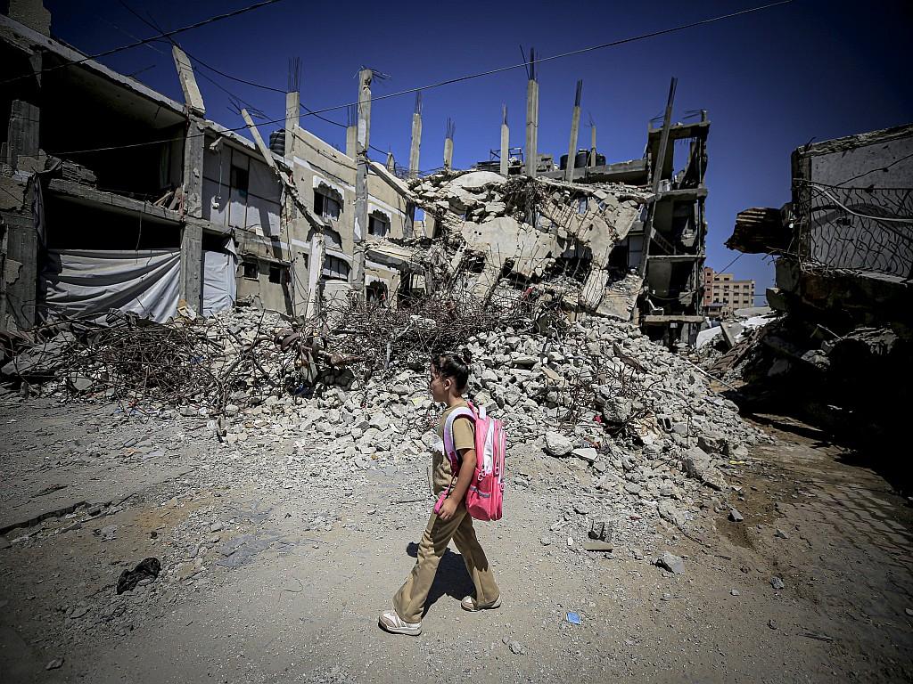 Mira Hamdoona, a seven-year-old Palestinian, walks through streets destroyed by Israeli airstrikes on her way to a temporary school.