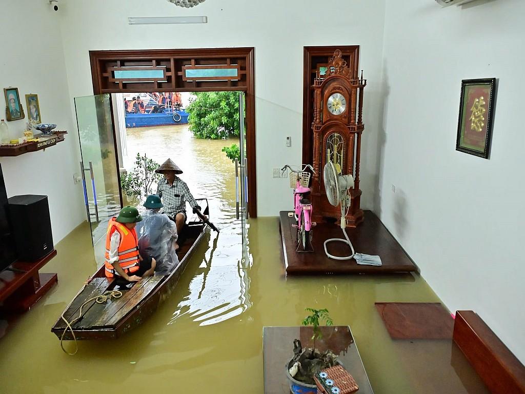 People use a boat to move through a flooded house.