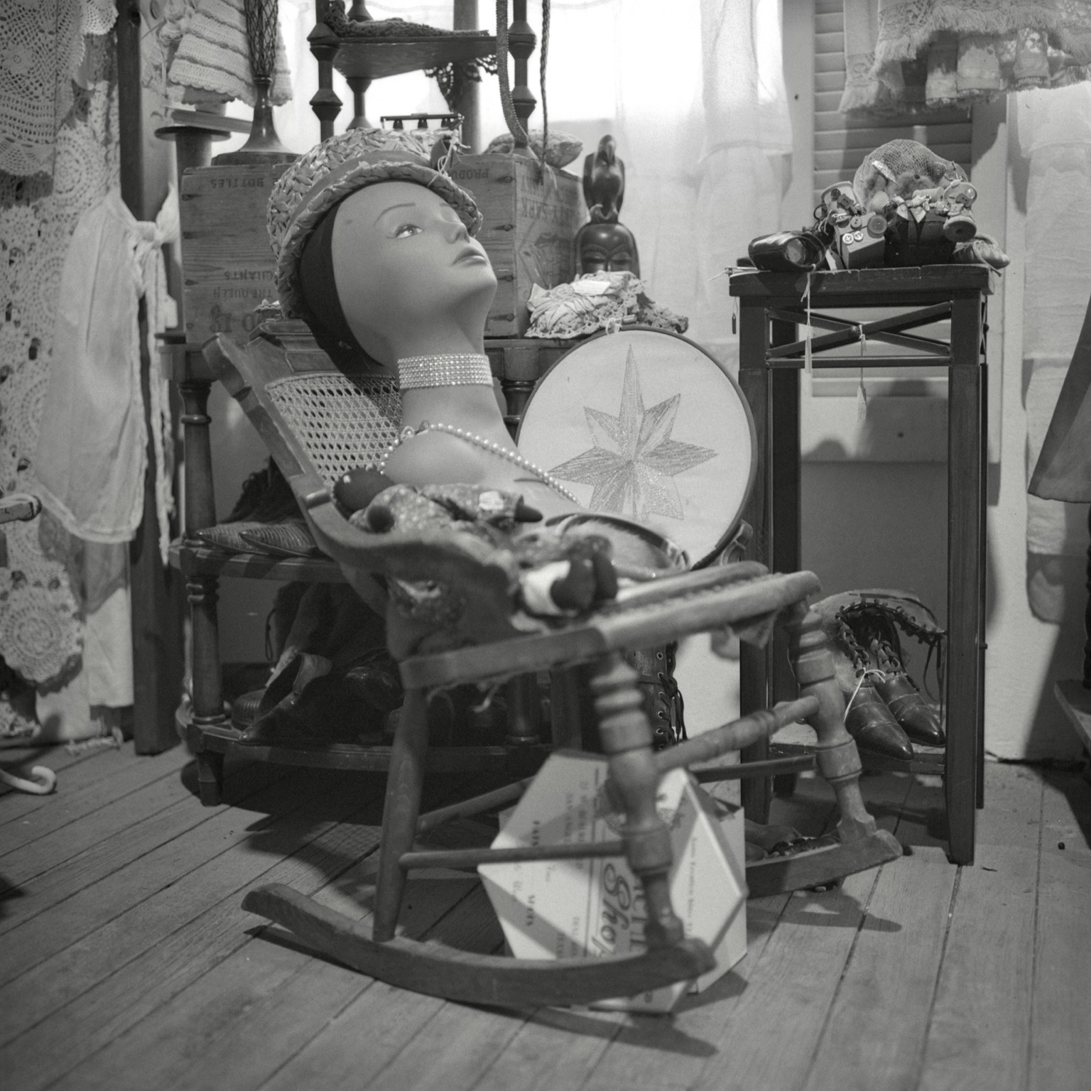 A black-and-white film photo. A mannequin’s head, wearing a hat and jewelry, chills out on a child’s rocking chair in Vintique Collective in Taylor, Texas. Saturday, August 8, 2026.