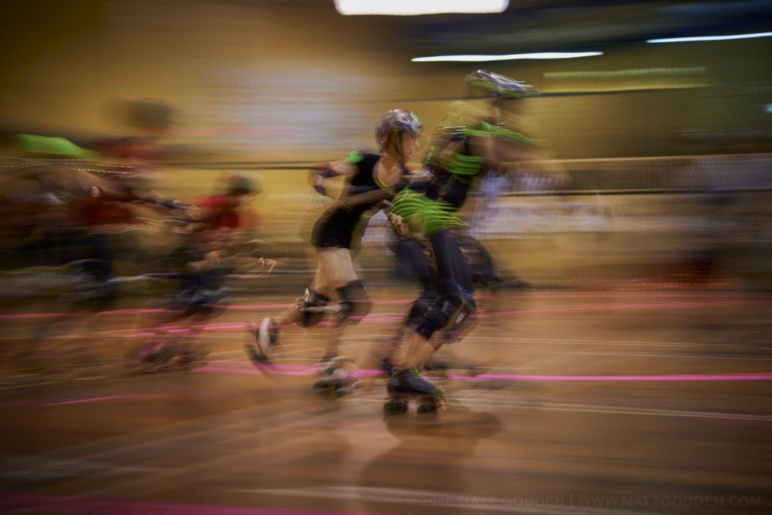 A long exposure image of roller derby competitors from the D'Viants (lime green), and the Screaming Assault Sirens (red). 2013/11/09