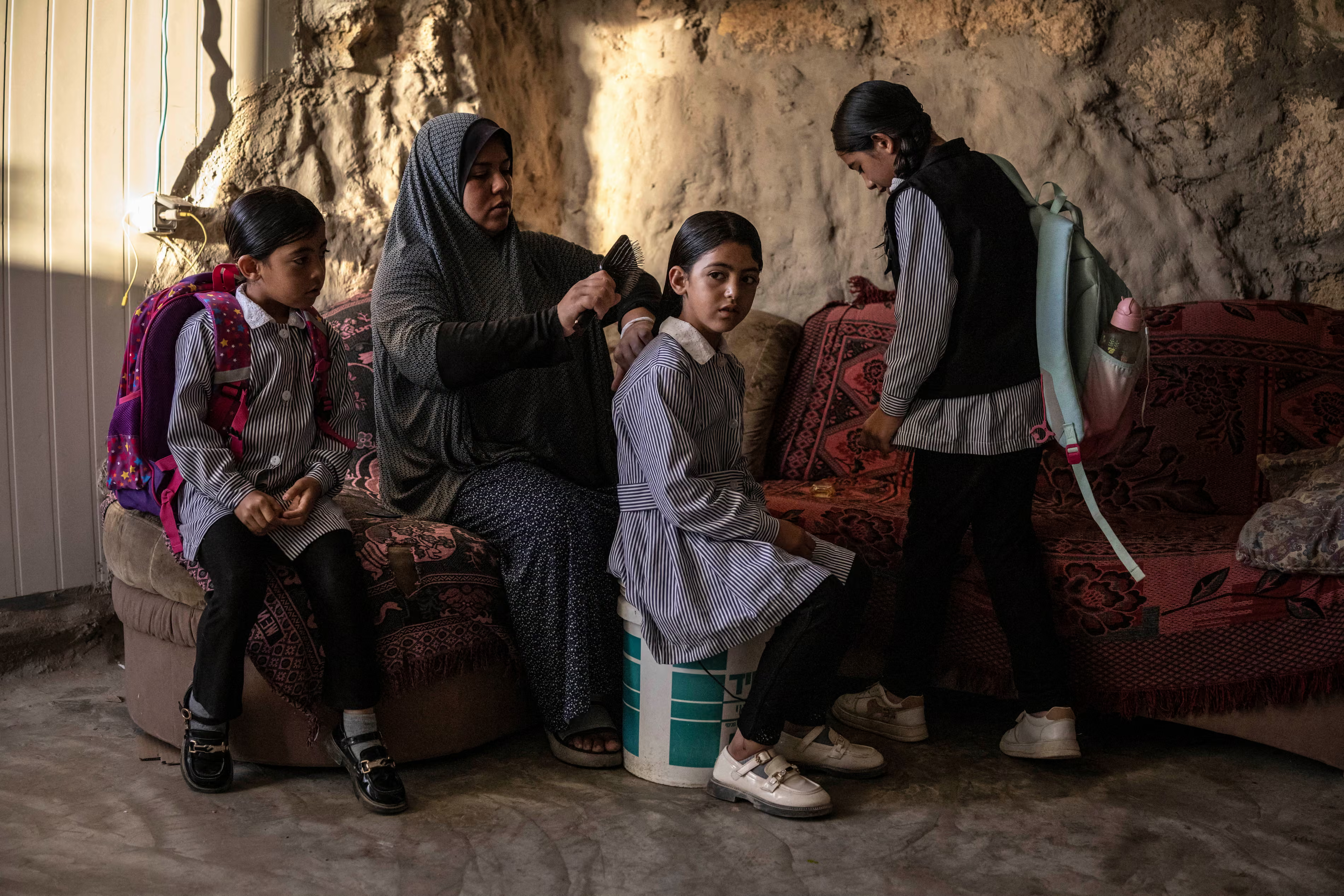 Arwa Amr brushes her daughter Layan’s hair as they prepare for school inside the cave that the family has turned into their home.
