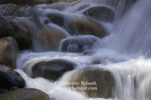 Water cascading down round and colourful boulders.