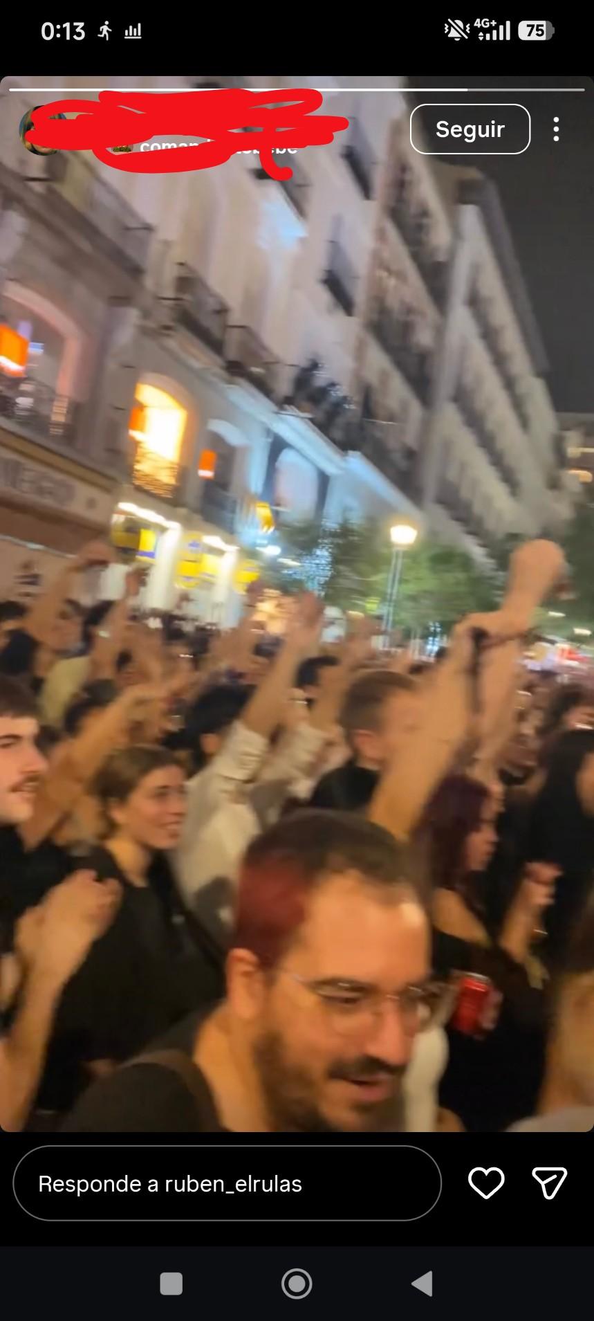 Yo hablando con una persona humana en Sol, mientras la gente alza las manos manifestando cosas