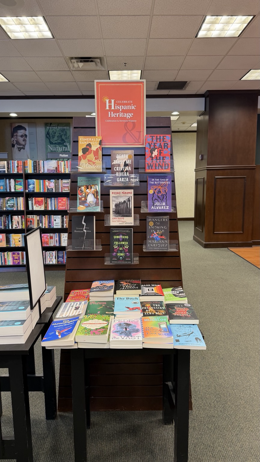 Small display of books on a shelf wall and table with a sign that reads "Hispanic Heritage month"