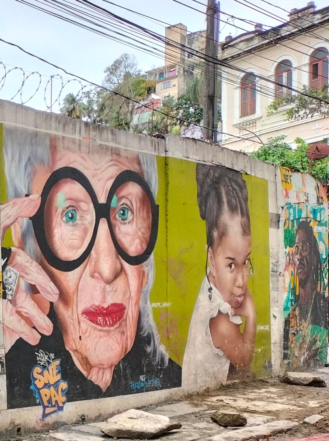 Camino escaleras de Selaron.Mujer mayor blanca con gafas de pasta negra,niña negra lanzando beso y hombre negro con gafas y rastas.