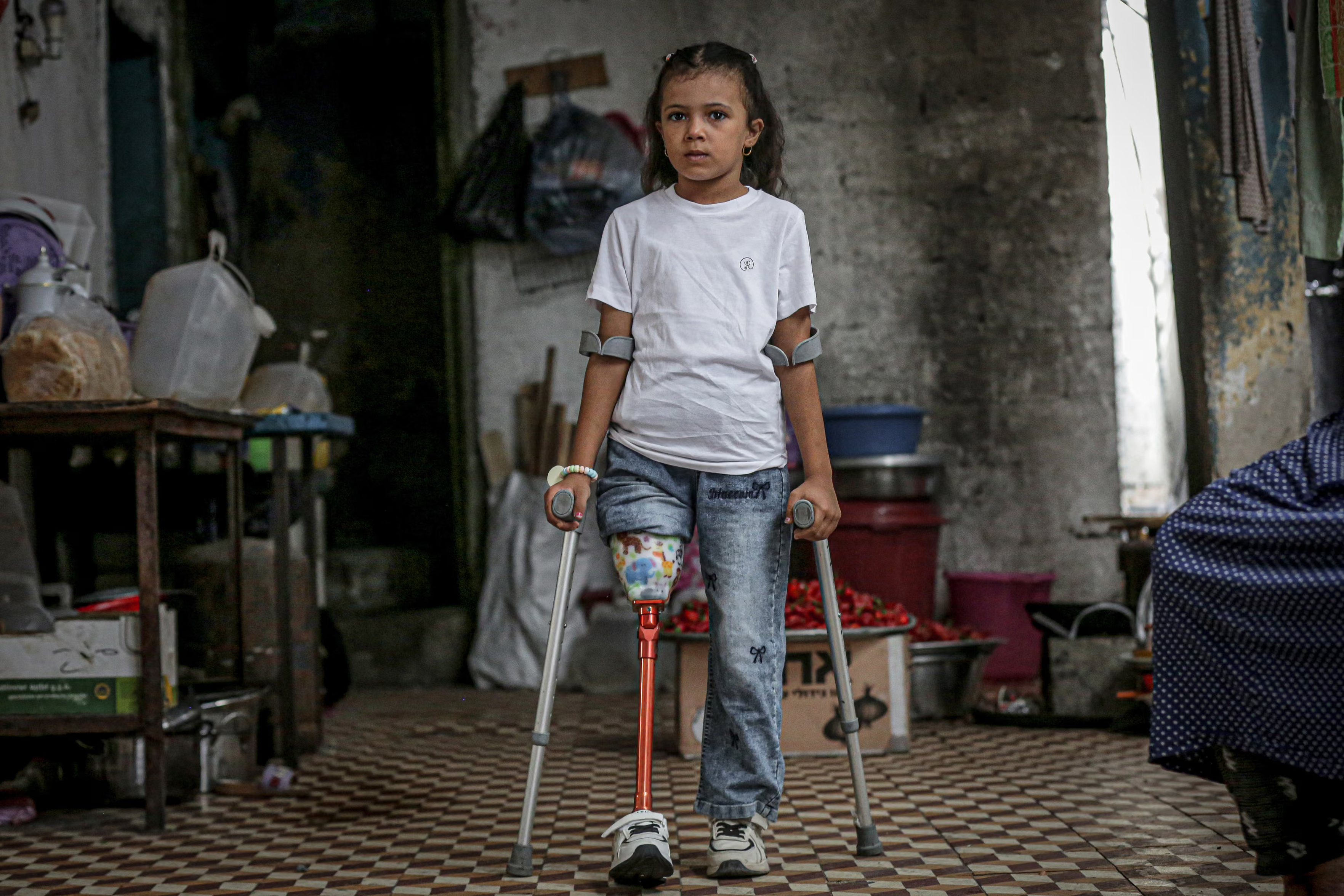 A six-year-old Palestinian girl, Sila Abu Aklein, walks with crutches.