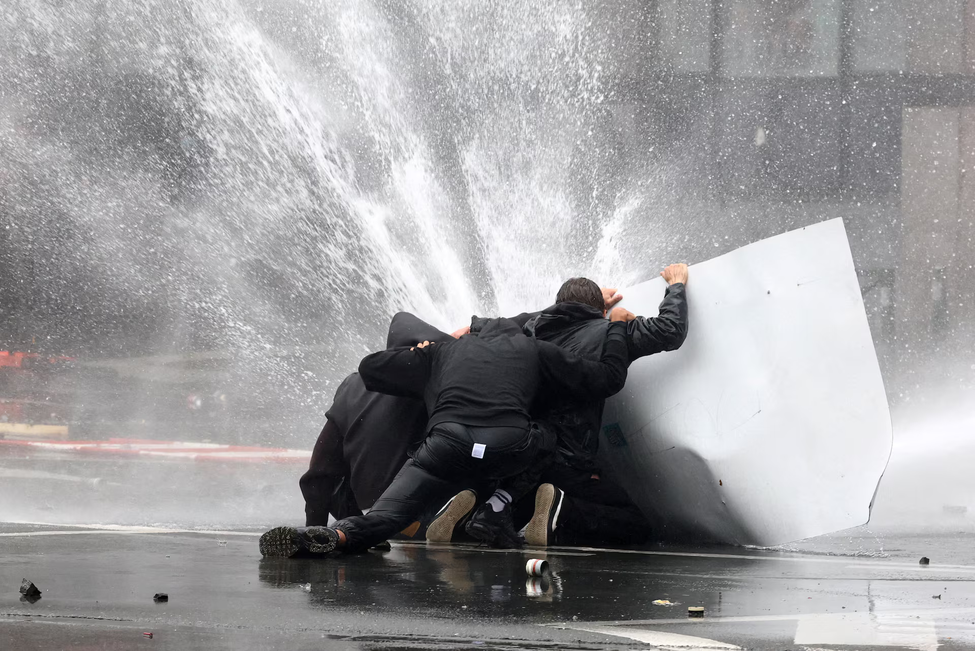 Demonstrators try to get cover from water cannons.