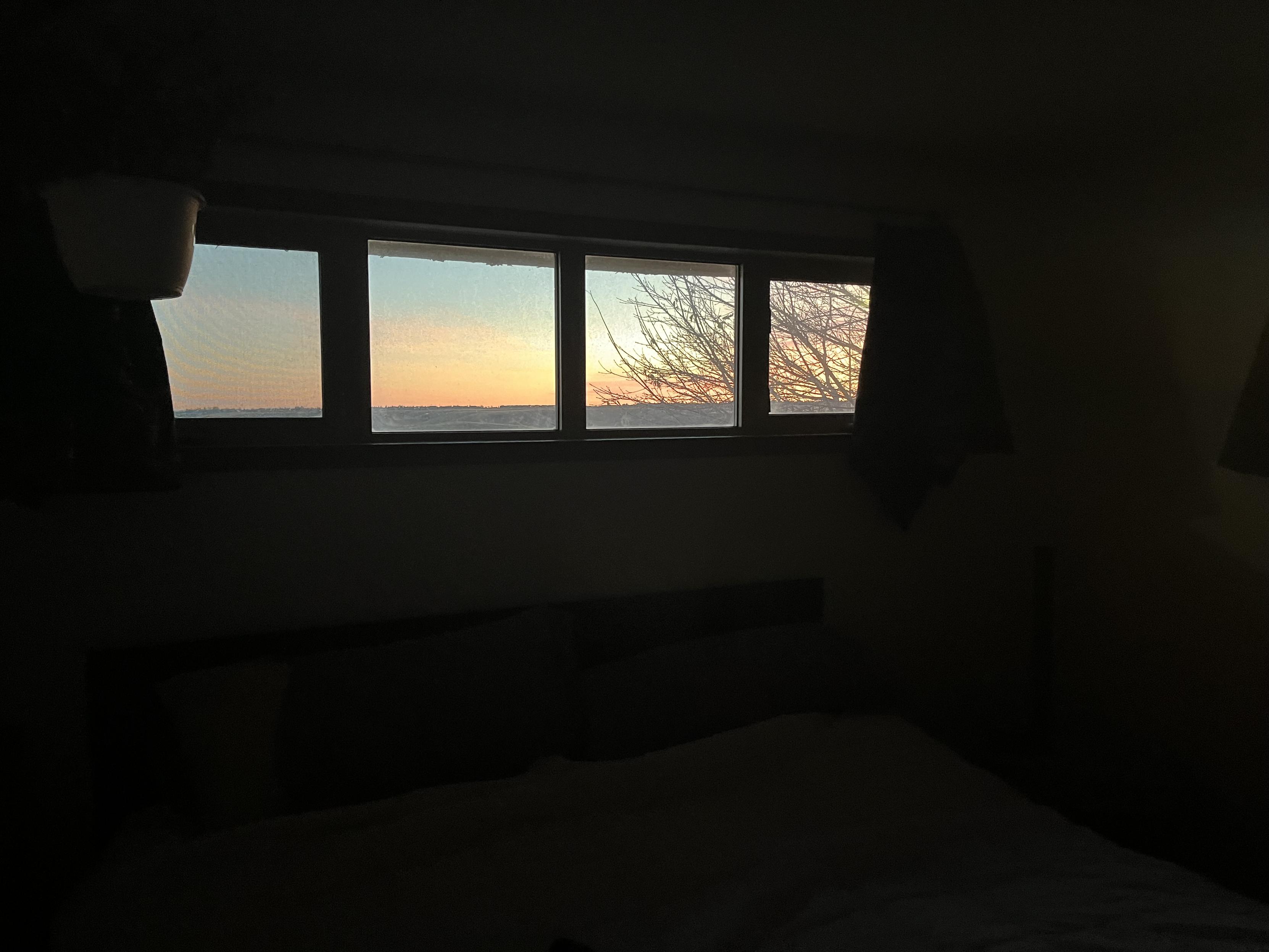 4 window panes with orange sunsetand 2 panes on right have spindly branches without leaves ssms Fall