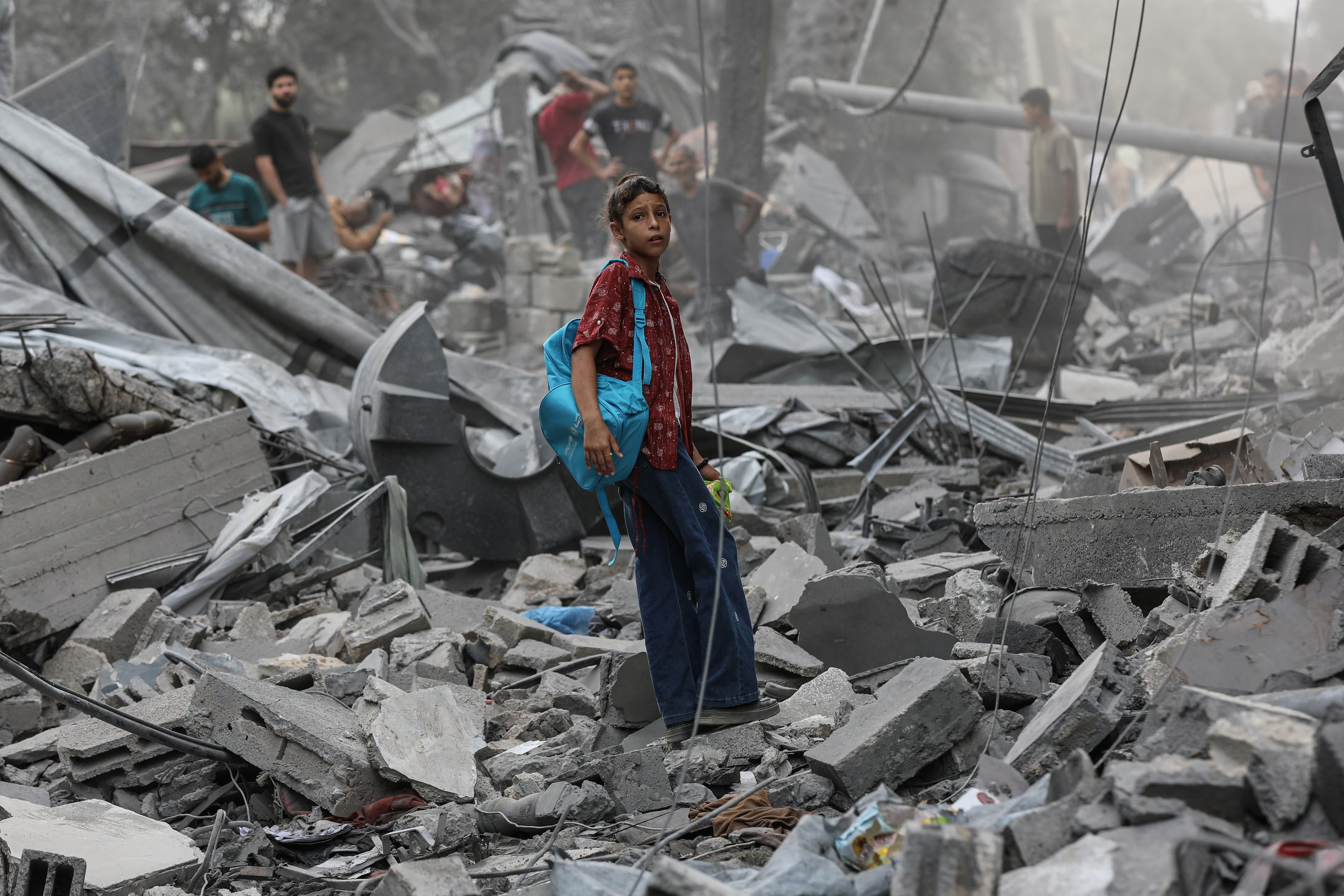 A Palestinian child stands amid the rubble of destroyed buildings after an Israeli airstrike.