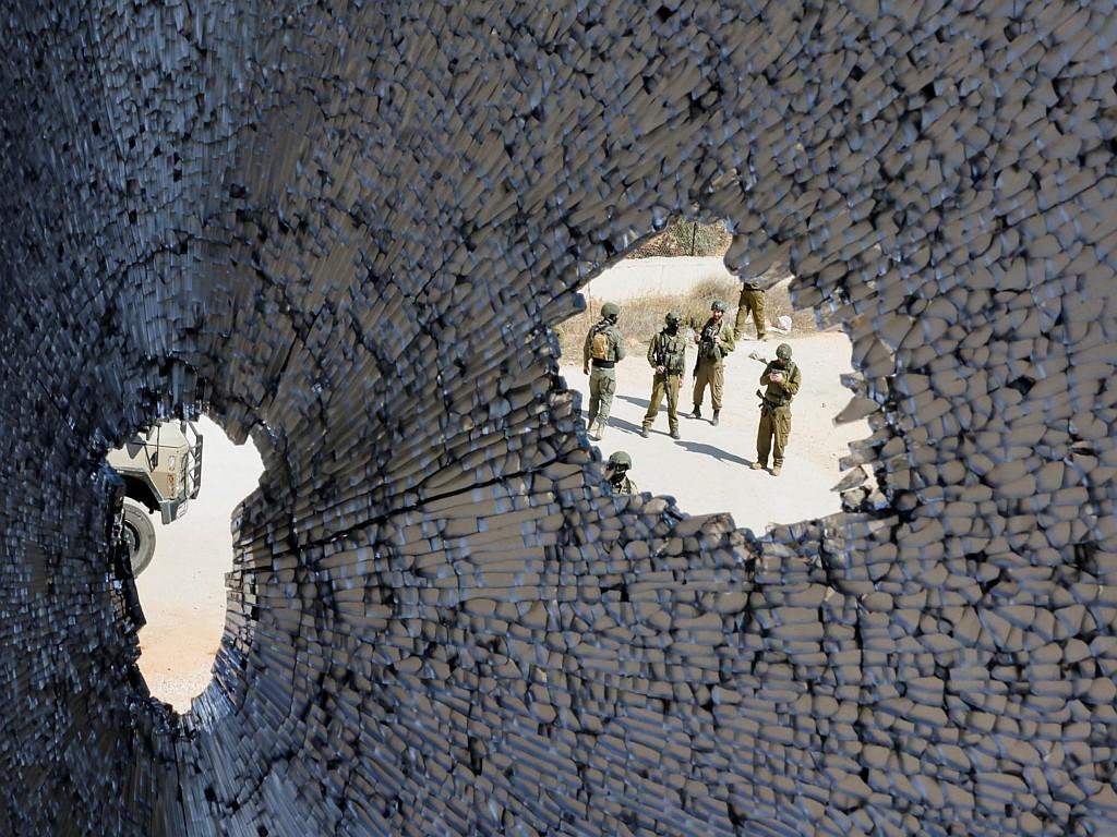 A view of Israeli soldiers through a broken window.