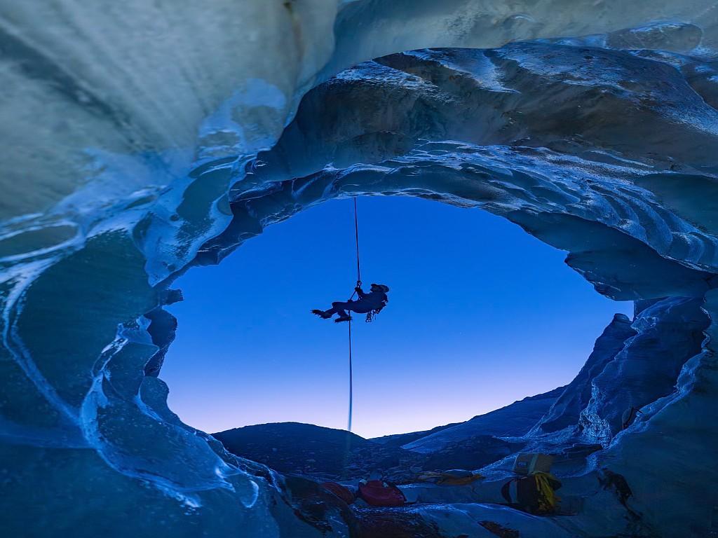 Abseiling past an ice cave at dusk.