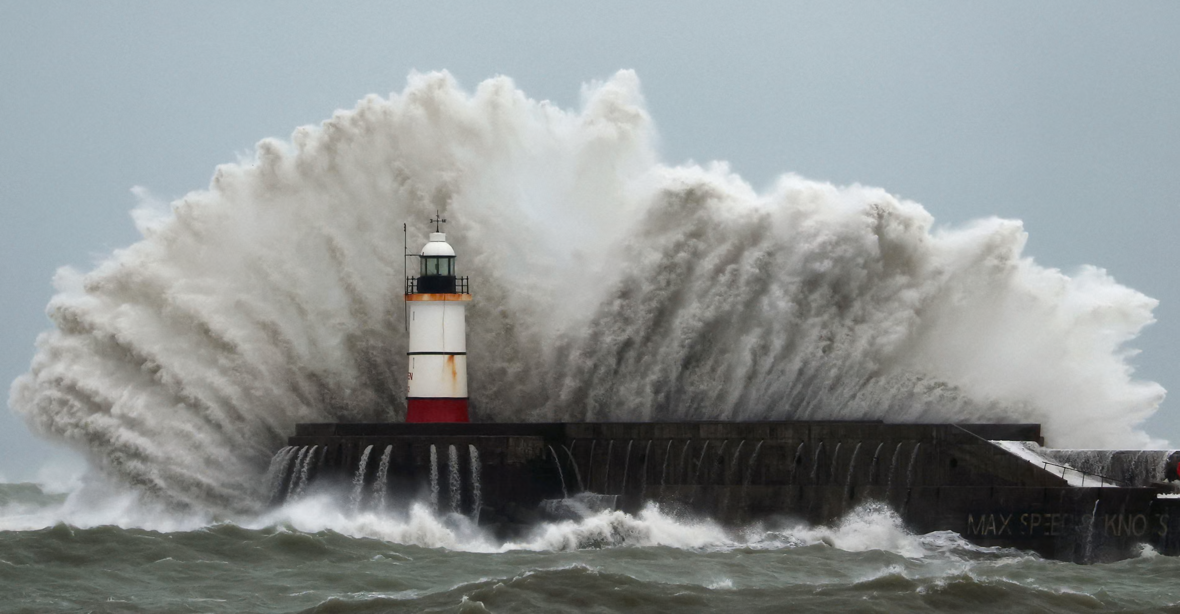 Waves crash over the lighthouse at Newhaven Harbour.