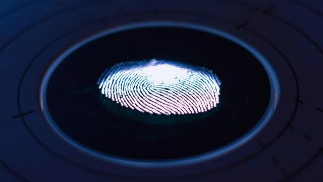 A glowing fingerprint on a dark circular scanner, representing identity controls for AI agents.